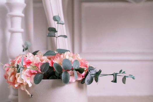 Hydrangea eucalyptus flowers bouquet in white box on white interior background.