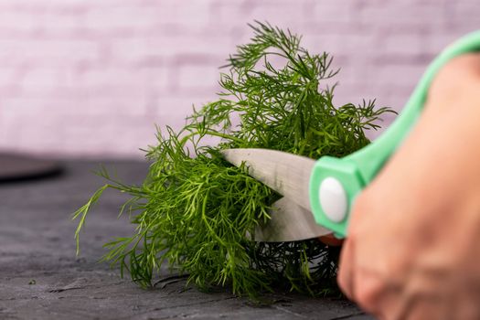 kitchen scissors cutting dill in the kitchen on a cutting board in the kitchen. Close-up of kitchen accessories. cooking. Fresh greens. Healthy eating.