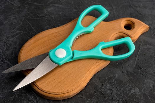 sharp kitchen scissors on a wooden cutting board in the kitchen. Close-up of kitchen accessories. cooking. Healthy eating. The cook's job. top side view