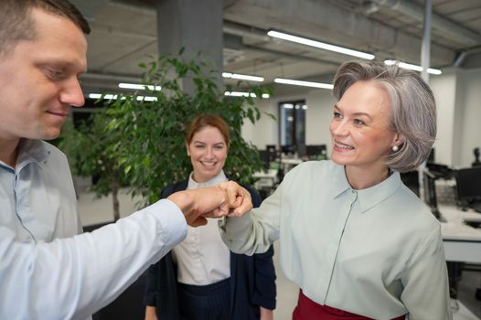 Caucasian man bumping his fists with colleagues as a sign of success