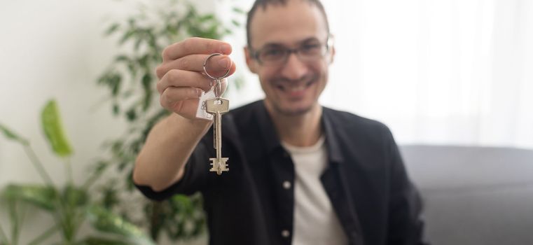 Portrait of handsome young man holding keys from house or auto on the white background