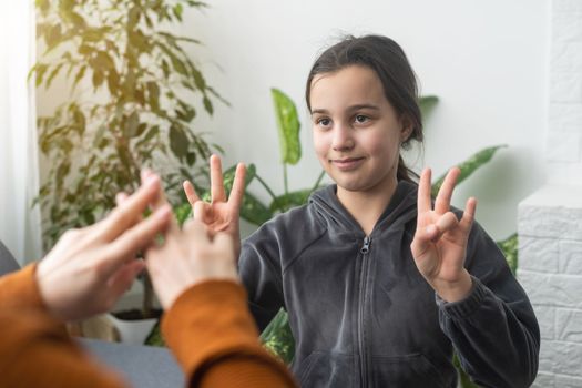 Small Caucasian teen girl child do articulation exercises with caring mother or teacher at home. Little kid pronounce sounds speak talk with tutor or coach, engaged in voice pronunciation together.