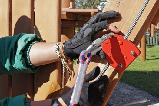 instructor explains how to use belay carabiners with ropes. On the obstacle course in the children's park. Hands with carabiner close up