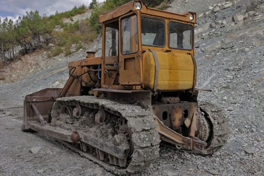 dirty bulldozer stands in the mud. Autumn construction site in a mountainous area with working machines