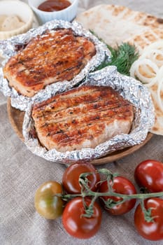 Grilled pork meat in foil with flapjack and vegetables. Summer rest concept