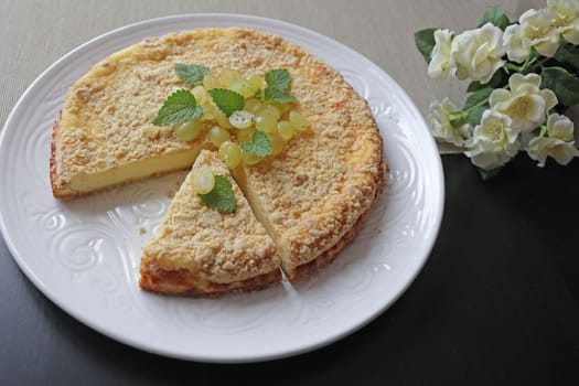 Round cottage cheese casserole decorated with fresh grapes and mint on a white plate. Fresh baked homemade cottage cheese casserole. Healthy food, baby meal.