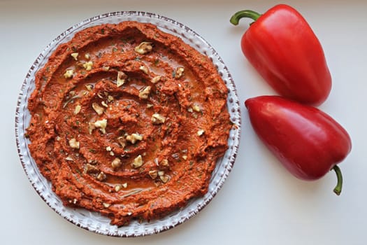 Muhammara, sauce of wholesome walnuts and roasted red bell peppers on a ceramic white plate. Copy space
