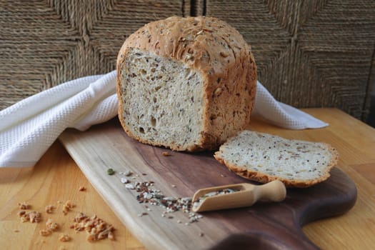 Whole grain rye bread with seeds. loaf of homemade whole grain bread and a cut off slice of bread. A mixture of seeds and whole grains. Healthy eating