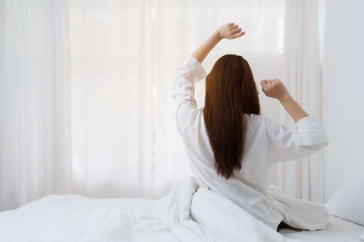 Beautiful asian woman has woken up on a white bed in the morning at home. lifestyle concept.