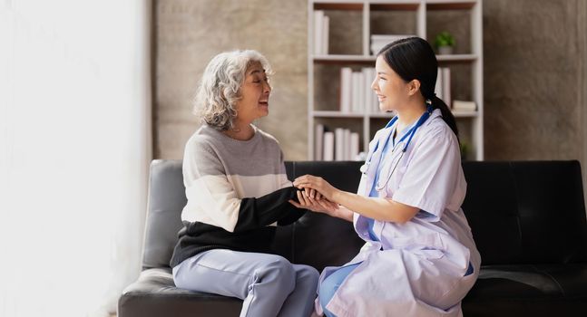 Home caregiver and senior woman holding hands. Professional Elderly Care. Professional care for elderly at nursing homes. Nurse holding hand of senior woman in rest home.
