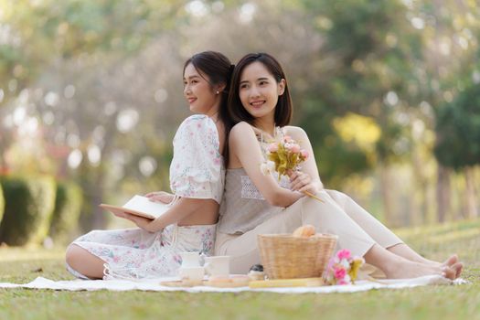 Beautiful woman and friend having picnic on sunny spring day in outdoor park. Valentine and LGBT concept