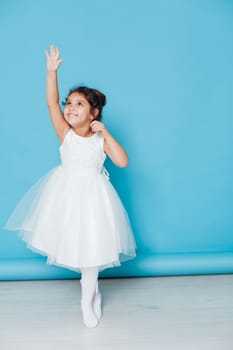 little girl in white dress ballerina dancing on blue background