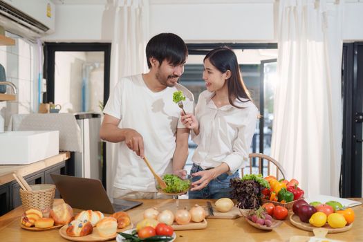 Young happy asian couple preparing healthy meal in kitchen at home. Food and healthy lifestyle concept