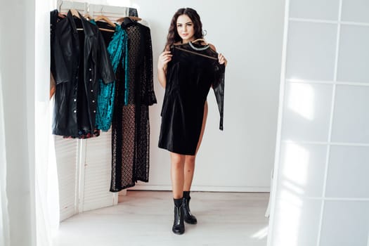 a brunette woman tries on a black dress in a store's wardrobe