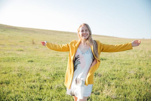 a beautiful blonde in a yellow jacket in nature green glade