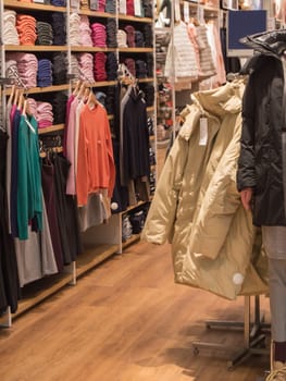 A colorful collection of women's autumn and winter clothing hangs on a hanger in the store.