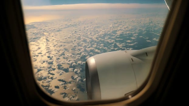 Blue Sky and white fluffy Clouds View from above through airplane's window at sunrise. High quality photo