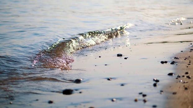 close-up, sea surf, tide, sea waves on the sand beach. in the rays of the sun, warm summer sunset,. High quality photo