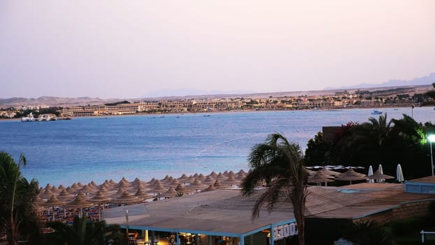 Egyptian resort. One of many quiet coves of the Red Sea, at sunset, at dusk. against the background of the outlines of buildings, palm trees, mountains . High quality photo