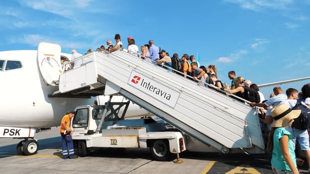 AIRPORT BORYSPIL, UKRAINE - OCTOBER 24, 2018: outdoors, passengers are waiting on plane gangway. They are getting ready to boarding the plane . Ukraine International Airlines. summer sunny day. High quality photo