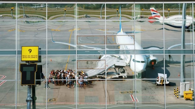 Ukraine International Airlines. passengers Boarding the plane and get ready to flight. reflection in mirrored windows of airport building. summer sunny day. High quality photo