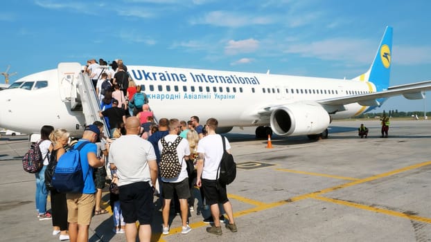 AIRPORT BORYSPIL, UKRAINE - OCTOBER 24, 2018: outdoors, passengers are waiting on plane gangway. They are getting ready to boarding the plane . Ukraine International Airlines. summer sunny day. High quality photo