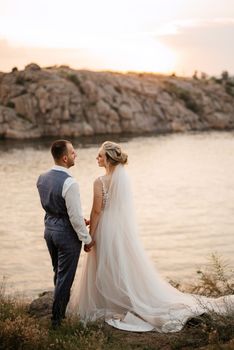 bride blonde girl and groom near the river at sunset light