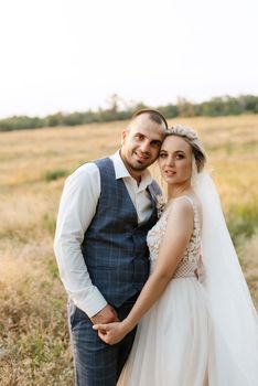 bride blonde girl and groom in a field at sunset light