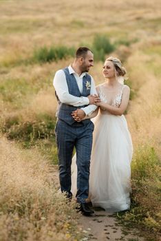 bride blonde girl and groom in a field at sunset light