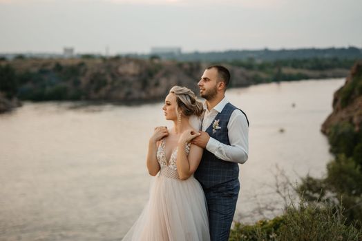 bride blonde girl and groom near the river at sunset light