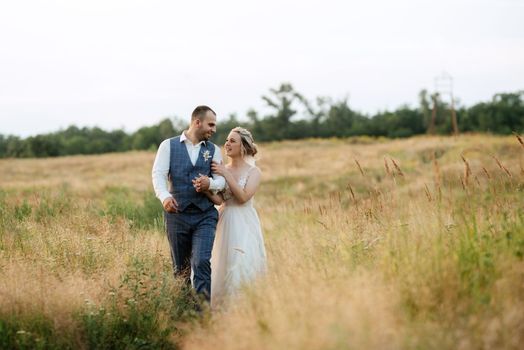 bride blonde girl and groom in a field at sunset light