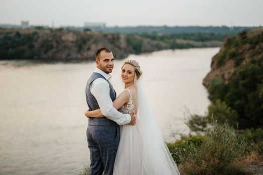 bride blonde girl and groom near the river at sunset light