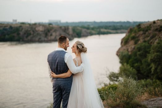 bride blonde girl and groom near the river at sunset light