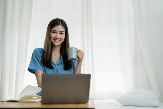 Happy, Relaxing Young beautiful Asian female watching movie or series on notebook in emotional smile happily while laying on the bed in her bedroom. Day off, Chill out and leisure concept...