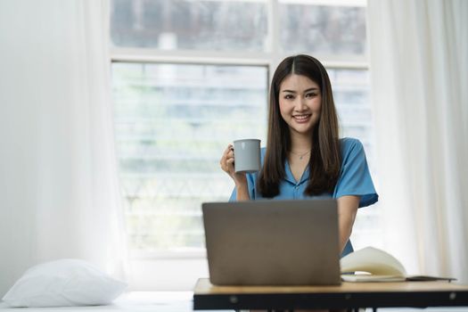 Happy, Relaxing Young beautiful Asian female watching movie or series on notebook in emotional smile happily while laying on the bed in her bedroom. Day off, Chill out and leisure concept...