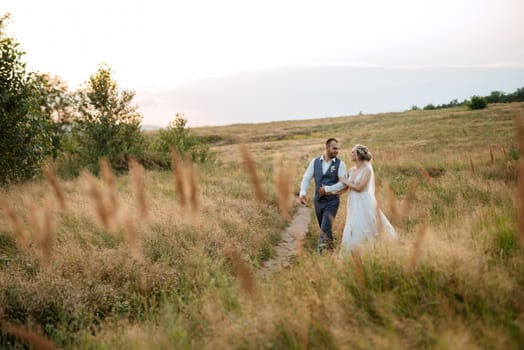 bride blonde girl and groom in a field at sunset light