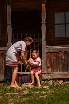 mother and daughter in Ukrainian folk dresses on the threshold of the house.