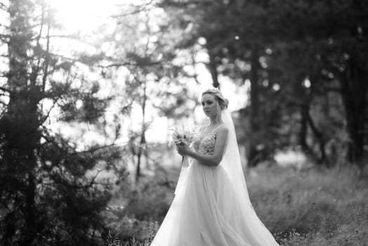 bride blonde girl with a bouquet in the forest in the sunset light