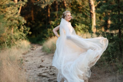 bride blonde girl with a bouquet in the forest in the sunset light