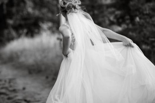 bride blonde girl with a bouquet in the forest in the sunset light