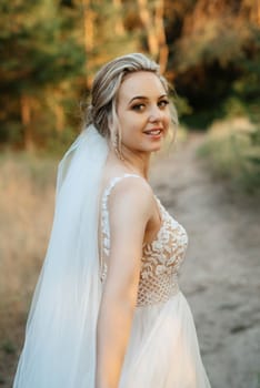 bride blonde girl with a bouquet in the forest in the sunset light