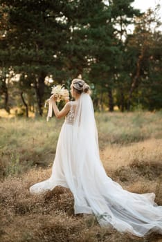 bride blonde girl with a bouquet in the forest in the sunset light