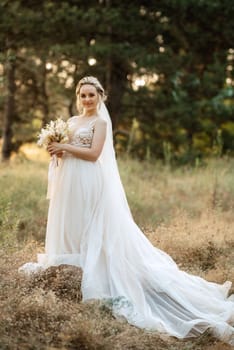 bride blonde girl with a bouquet in the forest in the sunset light