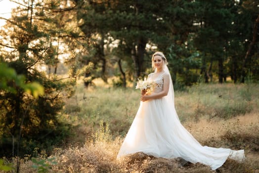 bride blonde girl with a bouquet in the forest in the sunset light