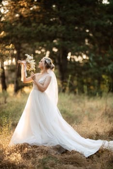 bride blonde girl with a bouquet in the forest in the sunset light