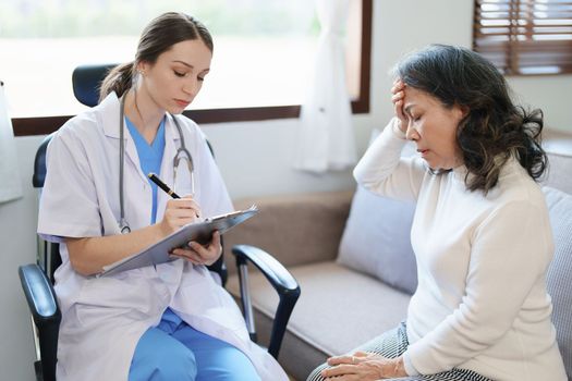 Portrait of a female doctor talking to an elderly patient showing headache