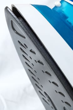 Blue iron on a white sheet, ironing, copy space