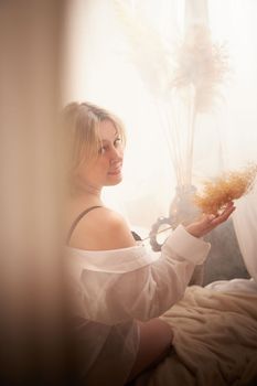 Portrait of sexual body positive adult lady woman in intimate in tender space indoors in a bedroom. Plump girl poses in black underwear and white shirt during boudoir style photo shoot