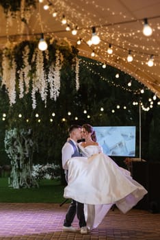 the first wedding dance of the bride and groom inside the restaurant hall in sunset light