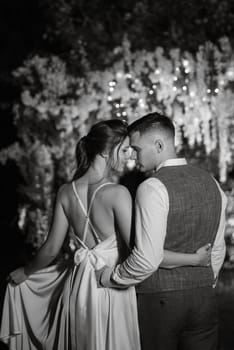 young couple of newlyweds on the evening illuminated arch